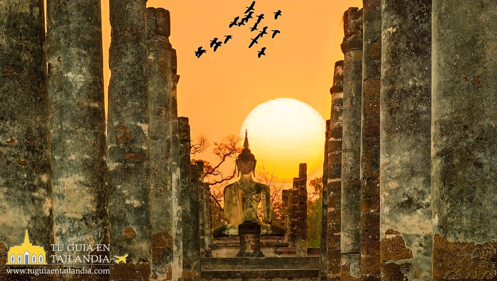 Puesta de sol entre las ruinas de Sukhothai con la silueta de un Buda