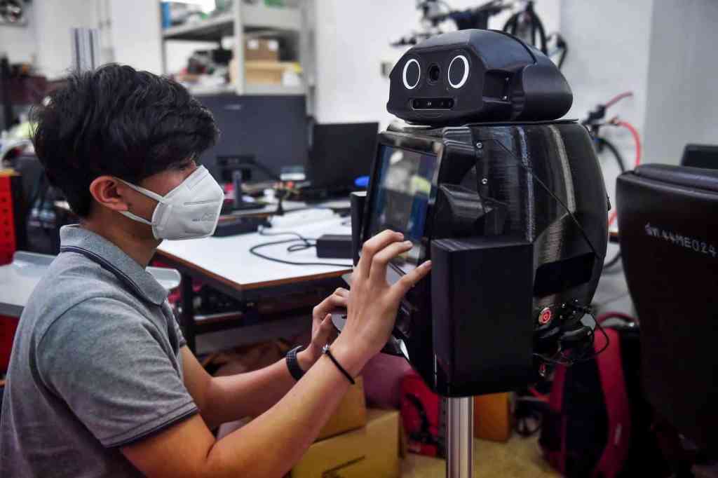 Tecnico programando el robot tailandes para combatir el coronavirus.