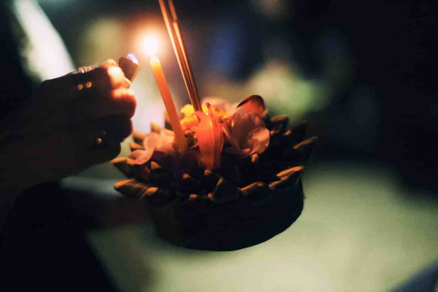 crop person burning candle on krathong