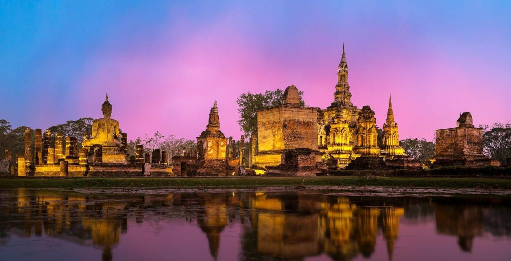 Templos iluminados al anochecer en el Parque Histórico de Sukhothai, Tailandia